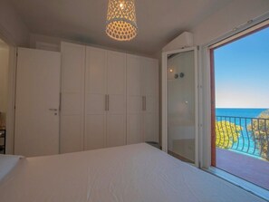 Ein Schlafzimmer mit Bett, Kleiderschrank und einem Balkon mit Meerblick.