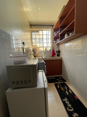 Eine Küche mit Mikrowelle, Toaster und Fenster mit Blick. Es gibt Schränke und eine Arbeitsfläche.