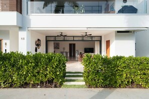 A modern building entrance with a covered walkway, a seating area, and a television. - 2BR Oceanfront • Pool & Beach • Sol de Arena A1 (Las Terrenas)
