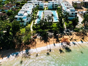 Ein Resort mit mehreren Gebäuden, einem zentral gelegenen Pool und einem Strand.