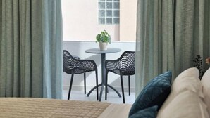 A room with a bed, a round table with two chairs, a potted plant, and a window with curtains. - Poet's Square Modern Residence 2 (Zakinthos)
