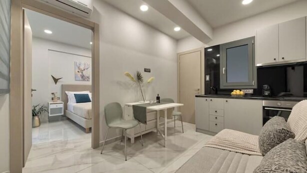 A compact hotel room with a bed, a desk, a chair, a kitchenette, and a bathroom. - Poet's Square Modern Residence 2 (Zakinthos)