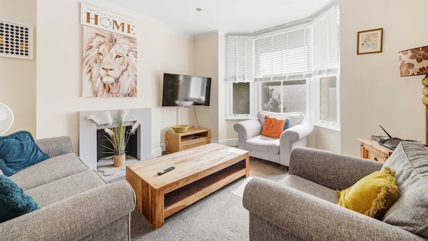 A living room with a fireplace, a television, and a sofa. - Peaceful 4-Bed Home in Aylesbury (Aylesbury)