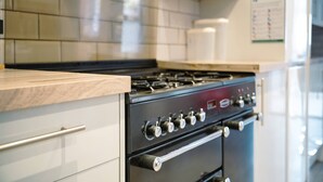 A kitchen with a stove, oven, and a tiled backsplash. - Peaceful 4-Bed Home in Aylesbury (Aylesbury)