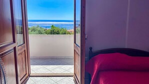 Una habitación con puerta de madera que da a un balcón con vista al océano.