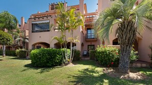 A building with multiple balconies, palm trees, and a well-maintained lawn. - 'Inner Paradise' Apartment with Shared Pool, Wi-Fi and Air Conditioning (Atalaya Isdabe)
