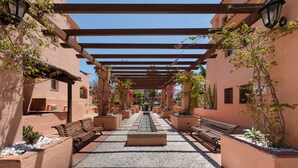 A corridor with benches, a central water feature, and a pergola structure. - 'Inner Paradise' Apartment with Shared Pool, Wi-Fi and Air Conditioning (Atalaya Isdabe)