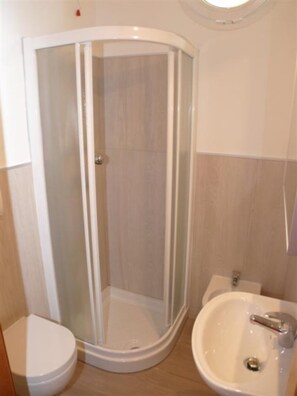 A bathroom with a glass-enclosed shower, a toilet, and a sink. - Shared Pool and Olive Orchard Garden Accommodation (San Michele al Tagliamento)