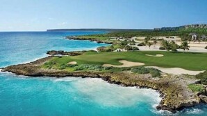 Un campo da golf costiero con vista sull'oceano e un edificio in lontananza.