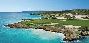 Ein Küsten-Golfplatz mit Blick auf das Meer und ein Gebäude in der Ferne.