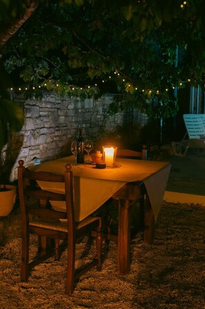 An outdoor dining area with a table, chairs, a candle, and string lights. - Tuscany Apartment (Vodnjan)