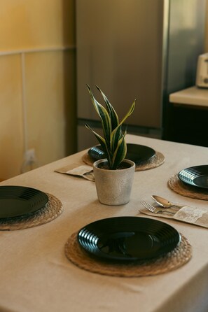 A table set for four with black plates, a potted plant, and a stainless steel appliance in the background. - Tuscany Apartment (Vodnjan)