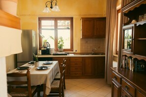 A kitchen with wooden cabinets, a dining table set for two, and a refrigerator. - Tuscany Apartment (Vodnjan)