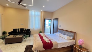 Una habitación de hotel con una cama, un sofá, una mesita de café y una planta en maceta.