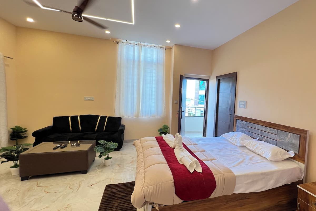 A hotel room with a bed, a sofa, a coffee table, and a potted plant.