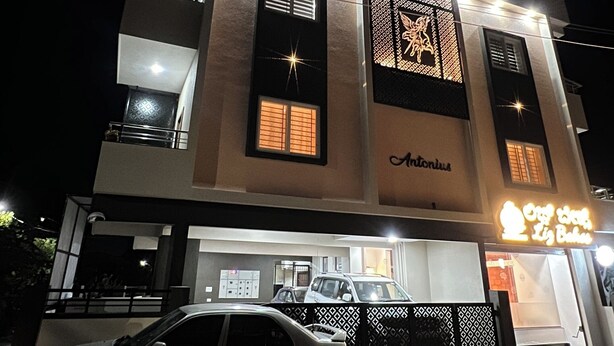 Un edificio de varios pisos con un coche estacionado frente a él, una entrada visible y un letrero con un logotipo.