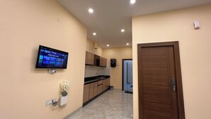 Una cocina moderna con un televisor de pantalla plana, una cafetera y un lavamanos.