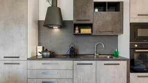 A modern kitchen with grey cabinets, a built-in oven, and a pendant light. - Bed and Breakfast 'Villa Giusy' with Private Garden (Verdellino)