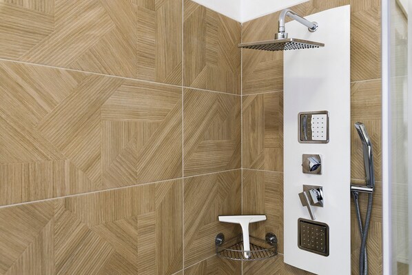 A shower area with a rain showerhead, handheld showerhead, and a handheld showerhead with a control panel.