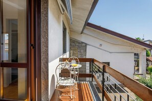 A balcony with a wooden floor, a metal railing, and a small table with chairs.