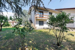 Uma casa moderna de dois andares com varanda, escadaria e um gramado bem cuidado.