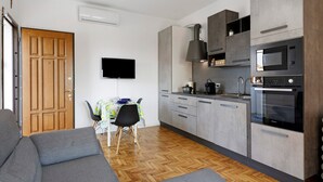A modern kitchen with grey cabinets, a built-in oven, and a flat-screen TV mounted on the wall. - Bed and Breakfast 'Villa Giusy' with Private Garden (Verdellino)