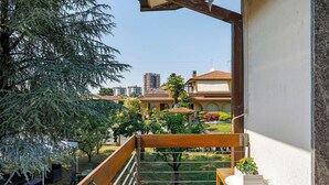 A balcony with a wooden bench, a small table with a plant, and a view of a residential area with houses and trees. - Bed and Breakfast 'Villa Giusy' with Private Garden (Verdellino)
