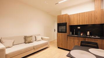 A modern kitchen with wooden cabinets, a built-in oven, and a dining area with a table and chairs.