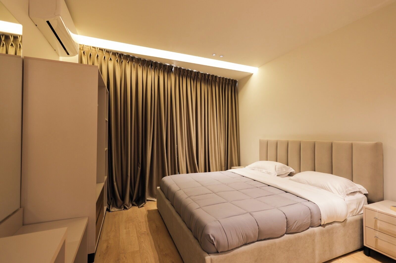 Quarto de hotel com cama, mesa de cabeceira e guarda-roupa.