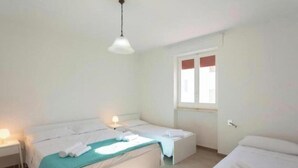 Ett hotellrum med två sängar, ett fönster och en hängande lampa.