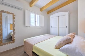Ein Schlafzimmer mit einem Bett, einem Kleiderschrank, einem Spiegel und einem Fenster.