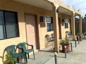 A building with a beige exterior, outdoor seating with chairs and tables, and potted plants. - San Felipe Studio One (San Felipe)