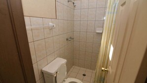 Ein kleines Badezimmer mit Fliesen, Toilette, Dusche und Vorhang.
