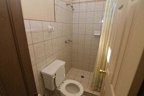 A small, tiled bathroom with a toilet, shower, and a curtain. - San Felipe Studio One (San Felipe)