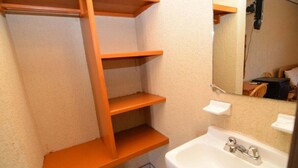 A bathroom with a white sink, a mirror, and wooden shelves.