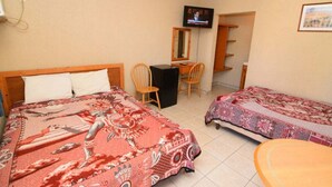 A hotel room with two beds, a desk, a chair, a television, and a small table.