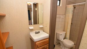 A bathroom with a sink, mirror, toilet, and shower curtain.