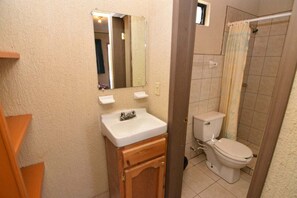 A bathroom with a sink, mirror, toilet, and shower curtain.