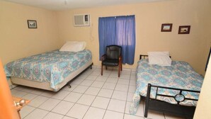 Une chambre avec deux lits, une chaise et un ventilateur de plafond.
