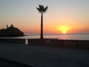 A sunset over a body of water with a palm tree and a lighthouse silhouette. - San Felipe Studio Five (San Felipe)