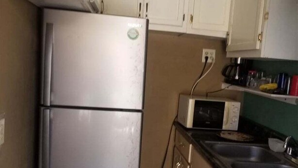 Une cuisine compacte équipée d’un réfrigérateur, d’un four à micro-ondes et d’un lave-linge.