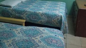 Une chambre avec deux lits, un téléviseur fixé au mur et une armoire en bois.