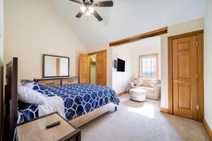 A bedroom with a bed, a desk, a TV, and a window.