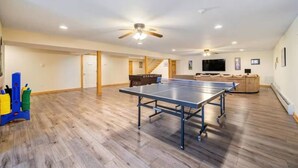 Una habitación amplia con mesa de ping pong, sofá y televisor.