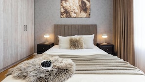Quarto com cama, duas mesas de cabeceira, um quadro na parede e um tapete de pele.