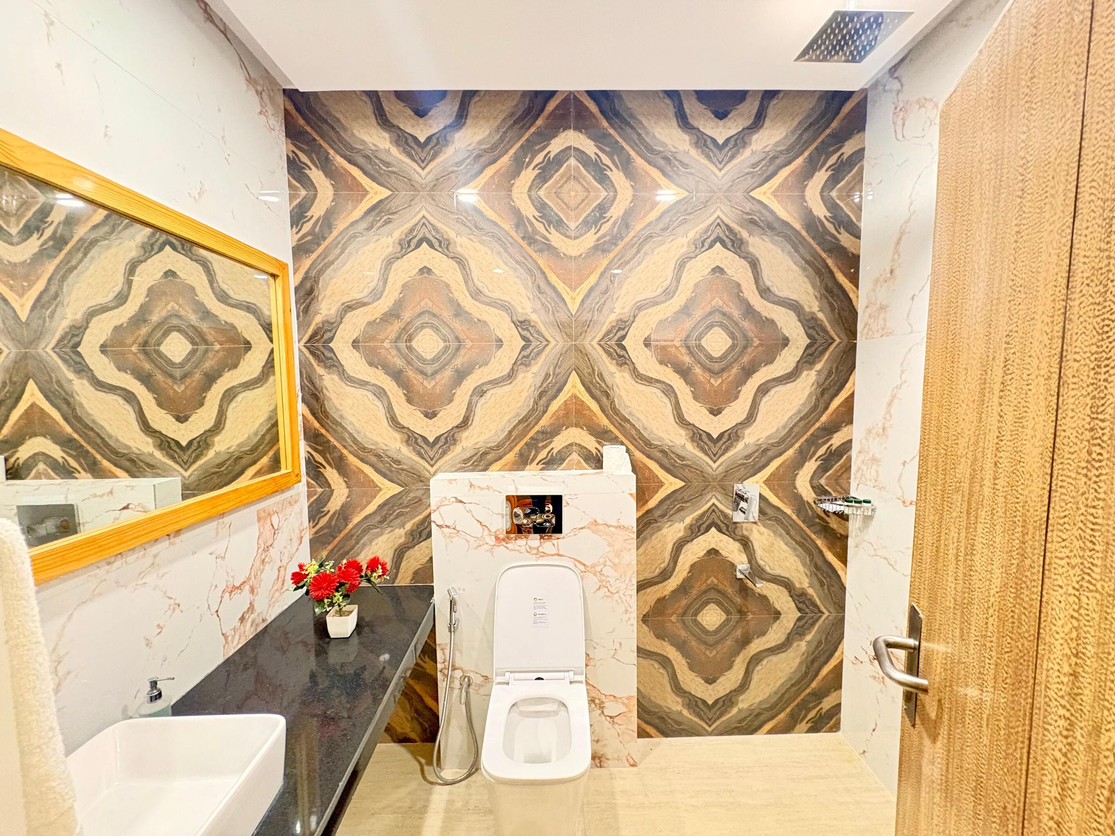 A bathroom with a toilet, sink, mirror, and patterned wall tiles.