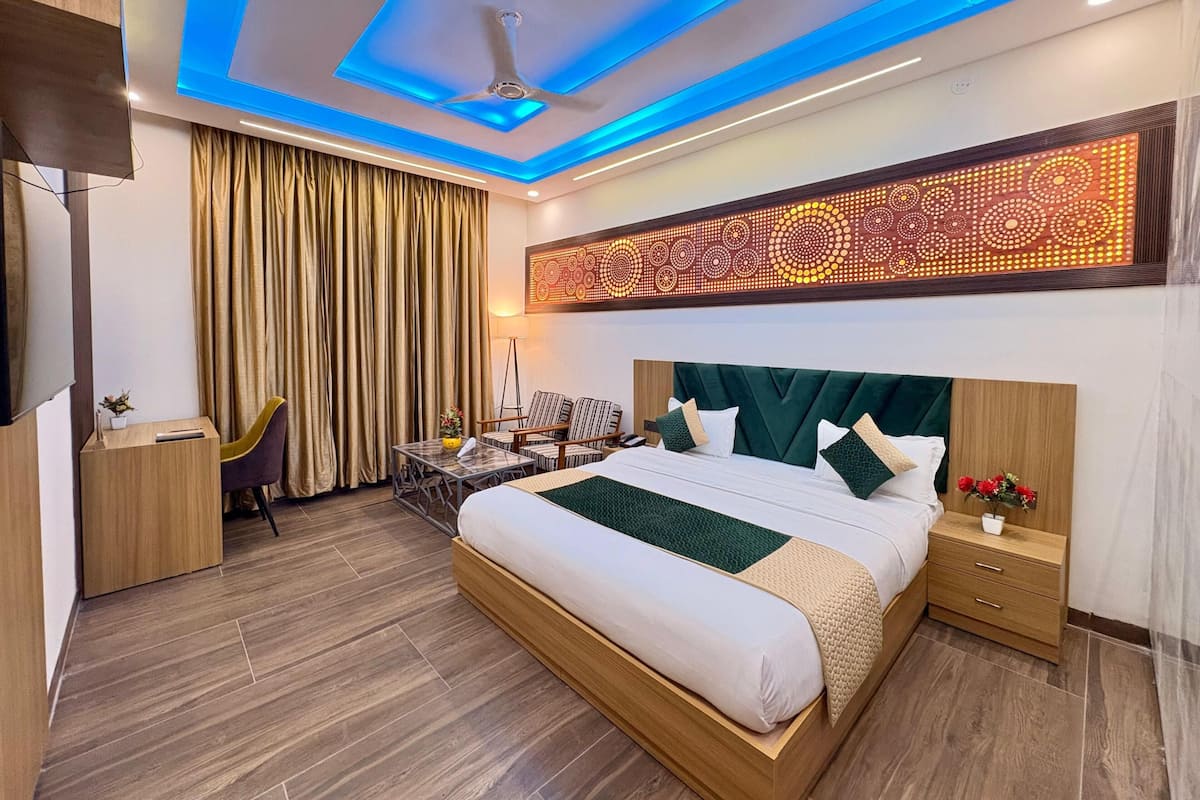 Una habitación de hotel moderna con una cama grande, un escritorio, una silla, un ventilador de techo y un panel de luz decorativo.