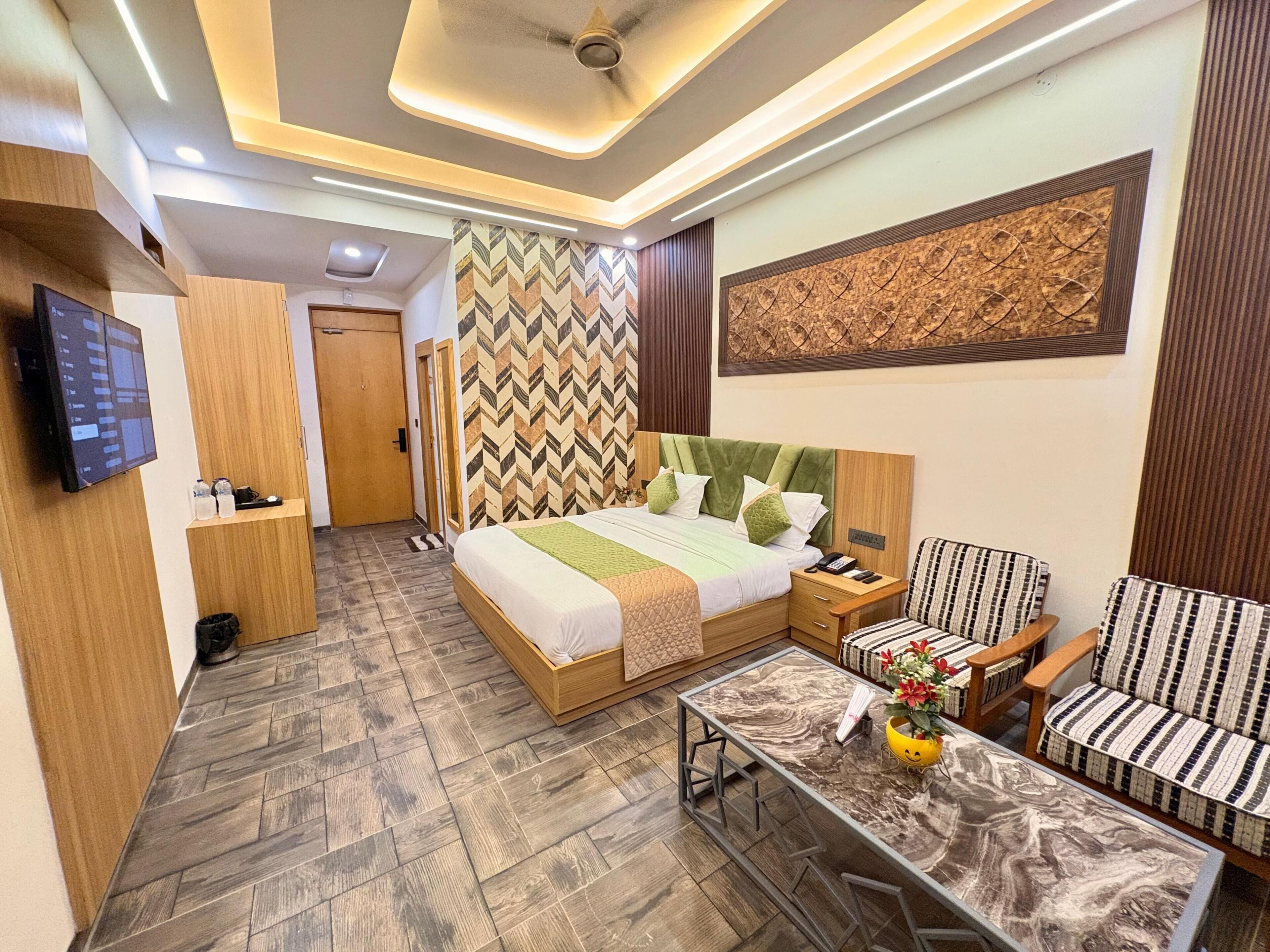 Une chambre d’hôtel moderne, équipée d’un lit, d’un canapé, d’une table basse, d’une télévision et d’un mur décoré d’un motif.