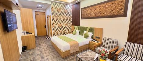 Une chambre d’hôtel moderne, équipée d’un lit, d’un canapé, d’une table basse, d’une télévision et d’un mur décoré d’un motif.