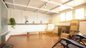 A room with a bench, a chair, a table, a potted plant, and a window. - Petito House - Cozy apartment surrounded by greenery. (Giugliano in Campania)